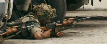 Movie still from “Hotel Mumbai” (2018), directed by Anthony Maras – A man in a military uniform is holding a rifle; Medium shot, High angle