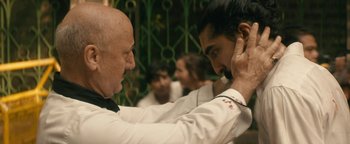 Movie still from “Hotel Mumbai” (2018), directed by Anthony Maras – Two men in white shirts and ties touching each other's hair; Close Up shot, Over the shoulder angle