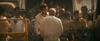 Movie still from “Hotel Mumbai” (2018), directed by Anthony Maras – A group of people standing around each other in a room; Medium shot, High angle