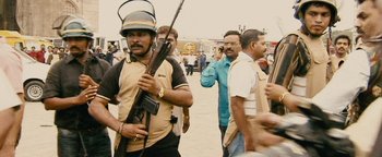 Movie still from “Hotel Mumbai” (2018), directed by Anthony Maras – A group of men walking down a street holding guns; Medium shot, High angle