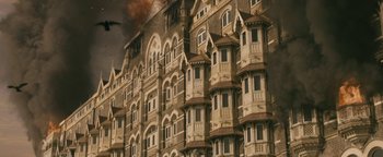 Movie still from “Hotel Mumbai” (2018), directed by Anthony Maras – A very tall building that has many balconies on it; Extreme Wide shot, High angle