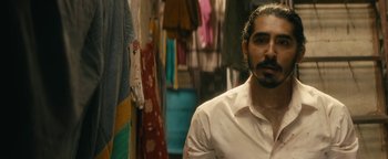 Movie still from “Hotel Mumbai” (2018), directed by Anthony Maras – A man in a white shirt is standing in front of a closet; Close Up shot, Over the shoulder angle