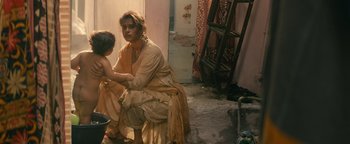 Movie still from “Hotel Mumbai” (2018), directed by Anthony Maras – A woman sitting on the ground with a child; Medium shot, High angle