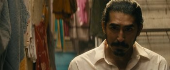 Movie still from “Hotel Mumbai” (2018), directed by Anthony Maras – A person wearing a white shirt; Close Up shot, Over the shoulder angle