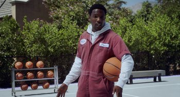 Movie still from “House Party” (2023), directed by Calmatic – A man holding a basketball on top of a basketball court; Medium shot, Over the shoulder angle