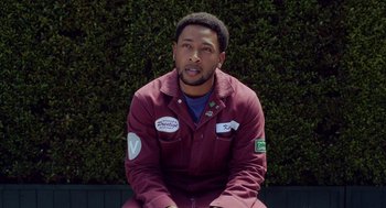 Movie still from “House Party” (2023), directed by Calmatic – A man sitting in front of a wall with bushes behind him; Close Up shot, Low angle