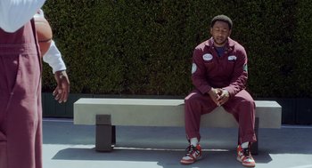 Movie still from “House Party” (2023), directed by Calmatic – A man sitting on top of a cement bench; Medium shot, Over the shoulder angle