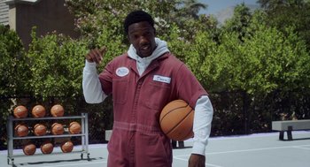 Movie still from “House Party” (2023), directed by Calmatic – A man holding a basketball on top of a basketball court; Medium shot, Over the shoulder angle