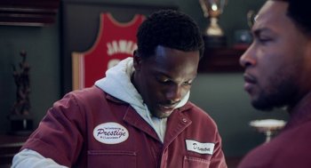 Movie still from “House Party” (2023), directed by Calmatic – A man in a red jacket looking down at his face; Close Up shot, High angle