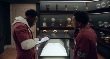Movie still from “House Party” (2023), directed by Calmatic – Two men are standing in front of a display case; Medium shot, Over the shoulder angle