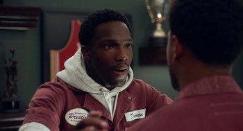 Movie still from “House Party” (2023), directed by Calmatic – A man talking to another man in front of a trophy; Close Up shot, Over the shoulder angle