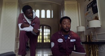 Movie still from “House Party” (2023), directed by Calmatic – Two men sitting on the floor in front of a laptop computer; Medium shot, Over the shoulder angle
