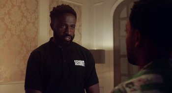 Movie still from “House Party” (2023), directed by Calmatic – A man in a black shirt talking to another man in a black shirt; Medium shot, Over the shoulder angle