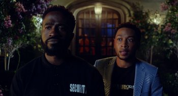 Movie still from “House Party” (2023), directed by Calmatic – A couple of men standing next to each other in a room; Medium shot, Over the shoulder angle