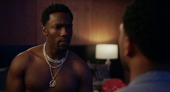 Movie still from “House Party” (2023), directed by Calmatic – A man wearing a chain around his neck talking to another man; Close Up shot, Over the shoulder angle