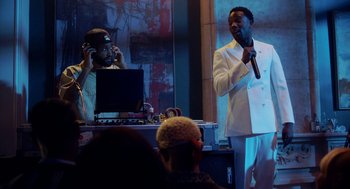 Movie still from “House Party” (2023), directed by Calmatic – A man holding a microphone while standing in front of another man; Medium shot, Over the shoulder angle