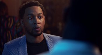 Movie still from “House Party” (2023), directed by Calmatic – A person sitting in a room; Close Up shot, Over the shoulder angle