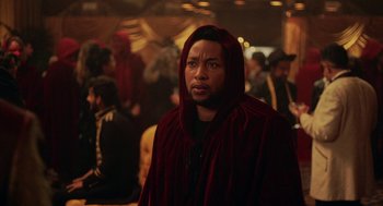 Movie still from “House Party” (2023), directed by Calmatic – A man in a red robe standing in front of a group of people; Close Up shot, Over the shoulder angle