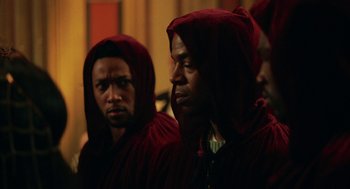 Movie still from “House Party” (2023), directed by Calmatic – A group of men in red hoods standing next to each other; Close Up shot, Over the shoulder angle