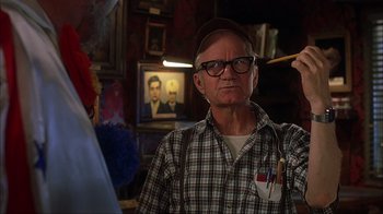 Movie still from “House of 1000 Corpses” (2003), directed by Rob Zombie – An older man is painting a picture with a brush in his hand; Close Up shot, Over the shoulder angle