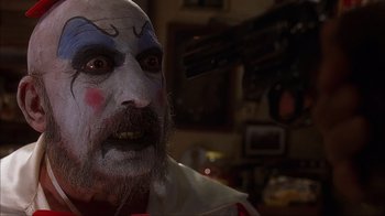 Movie still from “House of 1000 Corpses” (2003), directed by Rob Zombie – A person wearing a clown mask; Close Up shot, Low angle