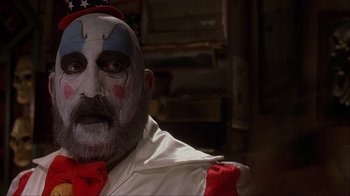Movie still from “House of 1000 Corpses” (2003), directed by Rob Zombie – A man with a clown face paint on his face; Close Up shot, Low angle