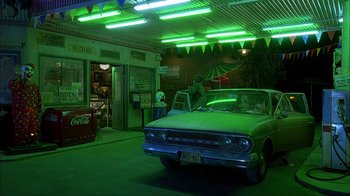 Movie still from “House of 1000 Corpses” (2003), directed by Rob Zombie – An old car is parked in a garage at night; Wide shot, High angle