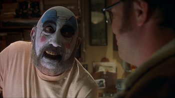 Movie still from “House of 1000 Corpses” (2003), directed by Rob Zombie – A man with a clown face painted on his face; Close Up shot, Over the shoulder angle