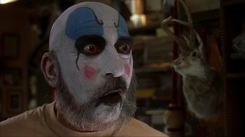 Movie still from “House of 1000 Corpses” (2003), directed by Rob Zombie – A person wearing a clown mask; Close Up shot, Low angle