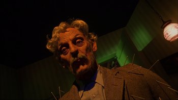 Movie still from “House of 1000 Corpses” (2003), directed by Rob Zombie – A man in a suit and a wig with a bunch of needles stuck to his face; Close Up shot, Low angle