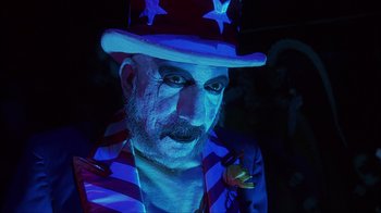 Movie still from “House of 1000 Corpses” (2003), directed by Rob Zombie – A man with a clown makeup and a hat; Close Up shot, Low angle