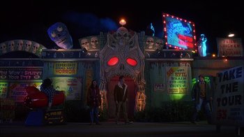 Movie still from “House of 1000 Corpses” (2003), directed by Rob Zombie – Two people standing in front of an entrance to an amusement park at night; Extreme Wide shot, High angle