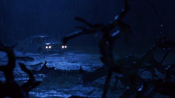 Movie still from “House of 1000 Corpses” (2003), directed by Rob Zombie – A car is driving in the rain at night; Extreme Wide shot, Low angle