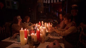 Movie still from “House of 1000 Corpses” (2003), directed by Rob Zombie – A group of people sitting around a table with candles; Wide shot, High angle