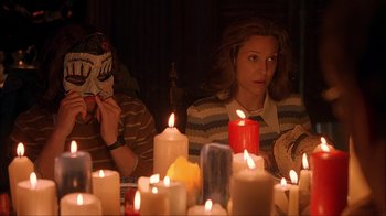 Movie still from “House of 1000 Corpses” (2003), directed by Rob Zombie – A group of people sitting around a table with candles; Medium shot, High angle