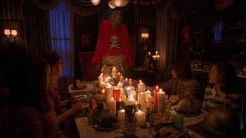 Movie still from “House of 1000 Corpses” (2003), directed by Rob Zombie – A group of people sitting around a table with candles on top of it; Wide shot, High angle