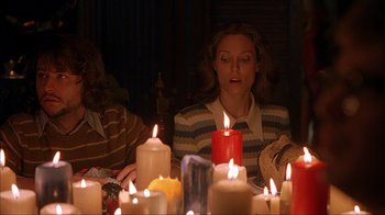 Movie still from “House of 1000 Corpses” (2003), directed by Rob Zombie – A woman sitting in front of a bunch of lit candles; Medium shot, High angle