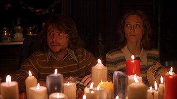 Movie still from “House of 1000 Corpses” (2003), directed by Rob Zombie – A man and a woman sitting in front of candles; Medium shot, Over the shoulder angle