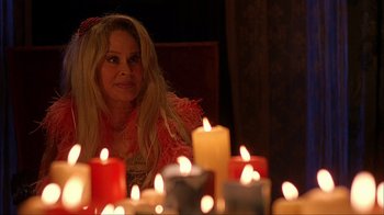 Movie still from “House of 1000 Corpses” (2003), directed by Rob Zombie – A woman sitting in front of a group of lit candles; Close Up shot, Over the shoulder angle