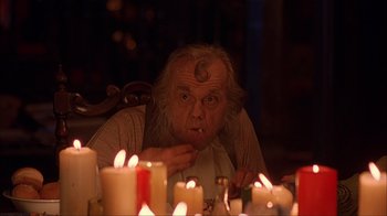 Movie still from “House of 1000 Corpses” (2003), directed by Rob Zombie – An old man sitting in front of a bunch of lit candles; Close Up shot, Over the shoulder angle