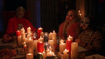 Movie still from “House of 1000 Corpses” (2003), directed by Rob Zombie – A woman sitting in front of a bunch of lit candles; Medium shot, High angle