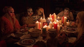 Movie still from “House of 1000 Corpses” (2003), directed by Rob Zombie – A group of people sitting around a table with candles; Medium shot, High angle