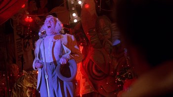 Movie still from “House of 1000 Corpses” (2003), directed by Rob Zombie – A man with a hat and a microphone in front of a crowd of onlookers; Medium shot, Low angle