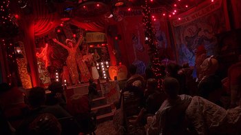 Movie still from “House of 1000 Corpses” (2003), directed by Rob Zombie – A crowd of people sitting and standing in a room; Wide shot, Low angle
