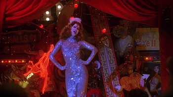 Movie still from “House of 1000 Corpses” (2003), directed by Rob Zombie – A woman in a silver dress standing in a room with red lights; Wide shot, Low angle