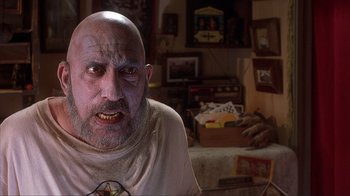 Movie still from “House of 1000 Corpses” (2003), directed by Rob Zombie – A man with a bald head is looking at the camera; Close Up shot, Low angle