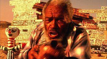 Movie still from “House of 1000 Corpses” (2003), directed by Rob Zombie – An old man with a gray beard is holding a knife; Close Up shot, Low angle