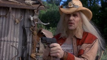 Movie still from “House of 1000 Corpses” (2003), directed by Rob Zombie – A man in a cowboy hat holding a gun in his hand; Close Up shot, Low angle