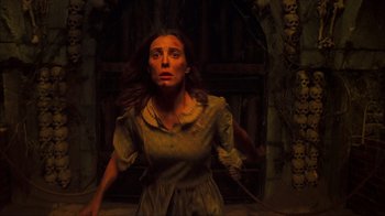 Movie still from “House of 1000 Corpses” (2003), directed by Rob Zombie – A woman with a knife in her mouth in a dark room; Medium shot, Overhead angle