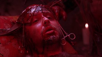 Movie still from “House of 1000 Corpses” (2003), directed by Rob Zombie – A man with blood all over his face and a pair of shears on his head; Close Up shot, Overhead angle